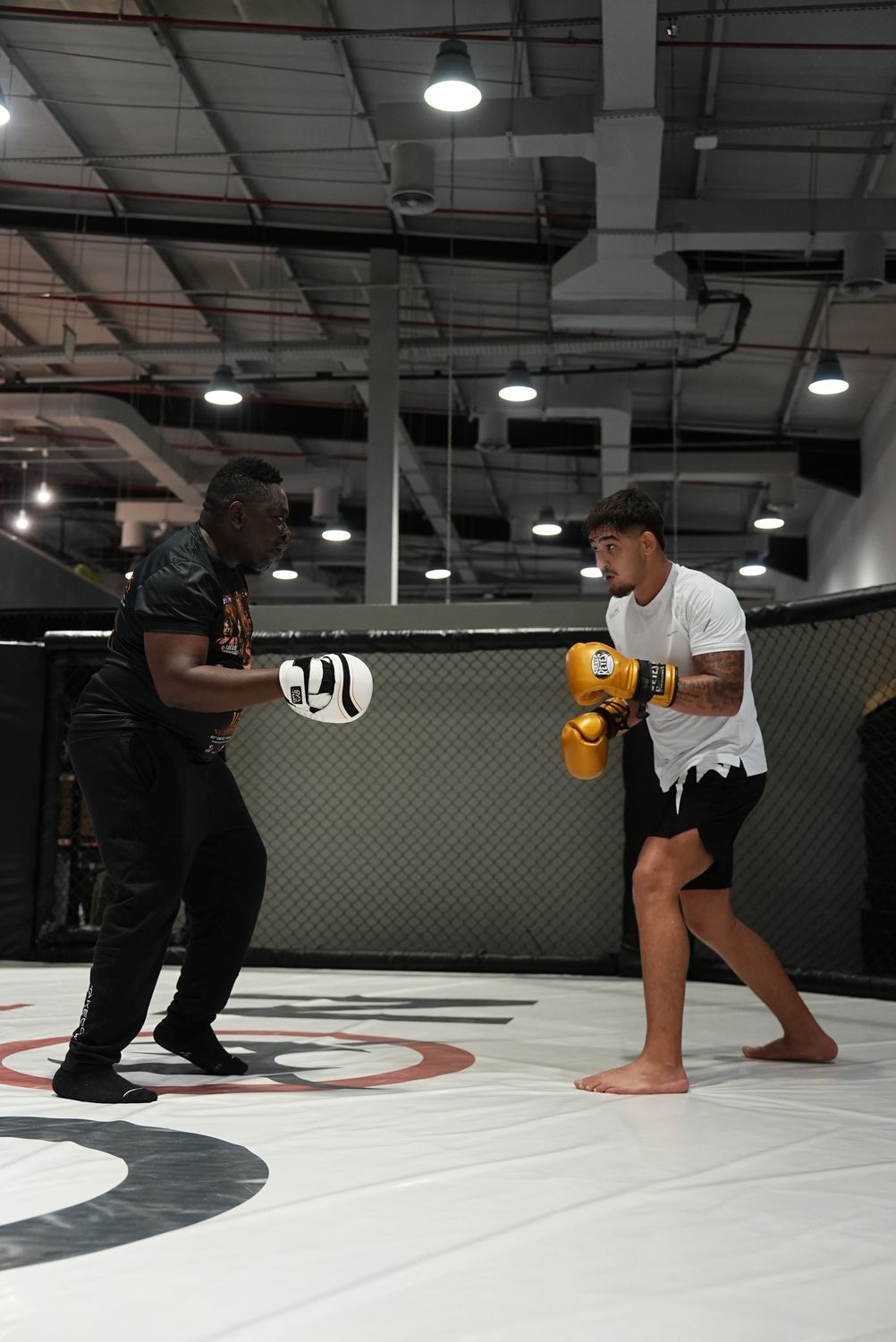 MMA fighter striking the pads with his coach in the cage