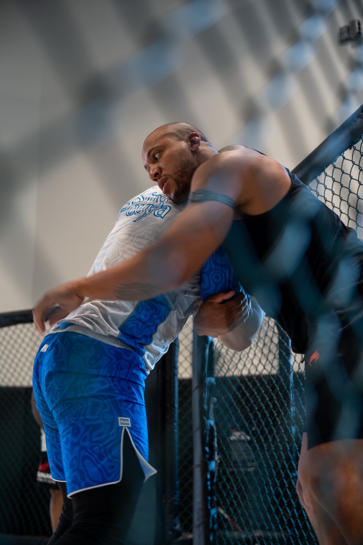 MMA fighter clinching his opponent against the cage on fight night